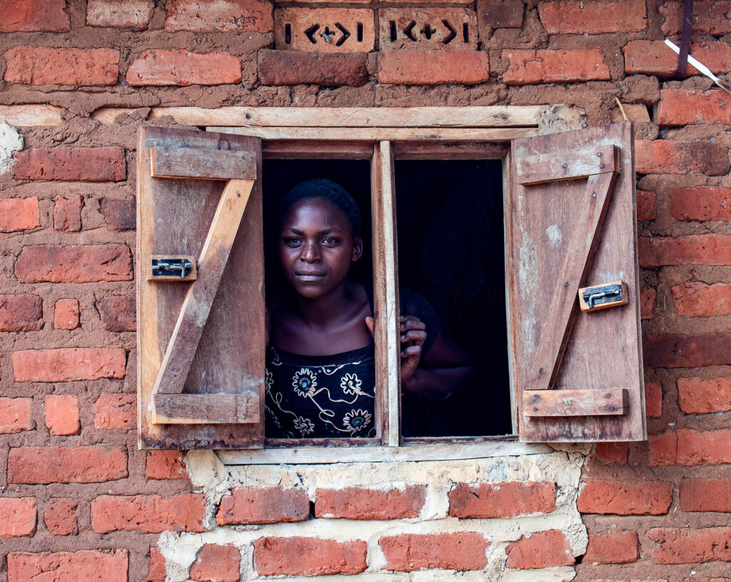 African Mother in a window looking at Fountain Of hope staff